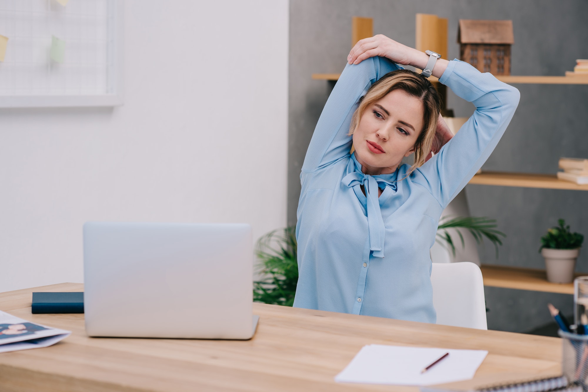 businesswoman stretching shoulders at workplace in office