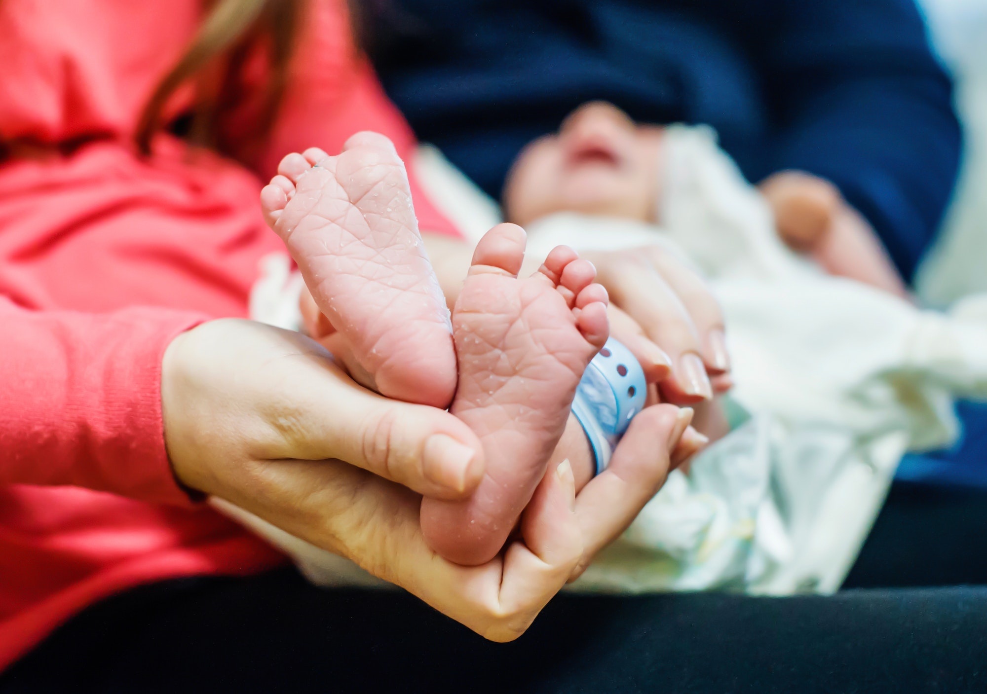 Mom holds the feet of a newborn baby baby. Young parents. Birth of a child